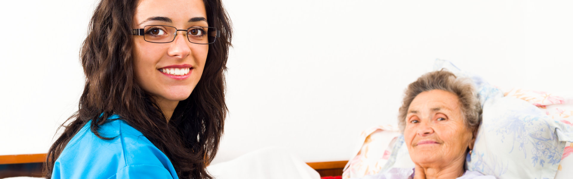 nurse with elder lying in bed