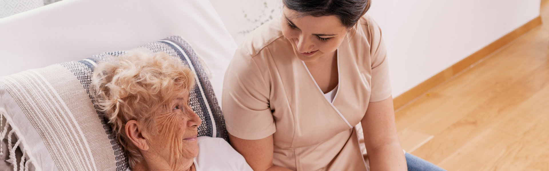 caregiver talking to elder lying in bed